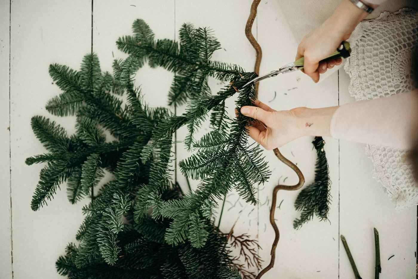 woman cutting fir bough - bring natural greenery in for the holidays